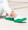 zapatillas de lona blanca con suela gruesa y puntera en color verde, cierre con cordones.
