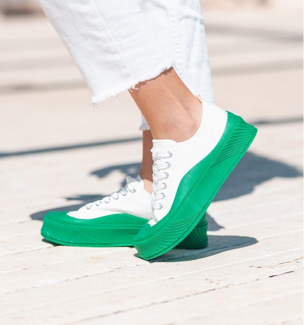 lateral zapatillas de lona blanca con suela gruesa y puntera en color verde, cierre con cordones.