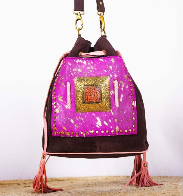 Bolsa tipo saco em pele e bolso frontal em pele lilás com pintas douradas. Peça em bronze e pedra no centro.