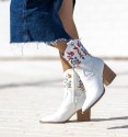 Botas de cowboy para mulher em pele branca, meio cano e salto de madeira, flores coloridas bordadas.