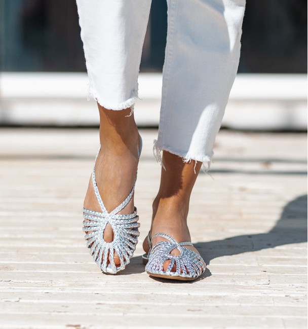 Silver clog-style ballerina flats in braided vegan leather straps. Fastened at the heel with a buckle