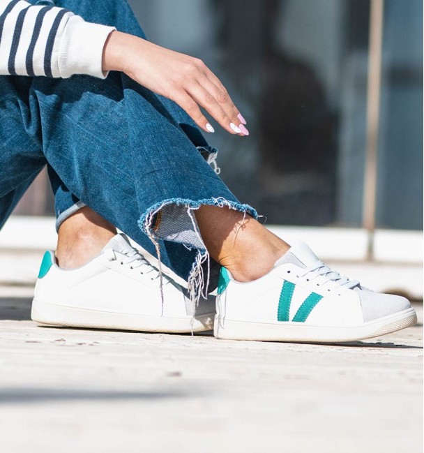 Deportivas cuerina vegana blanca con dos líneas verdes y cordones.