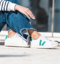 White vegan leather sneakers with two green lines and laces.