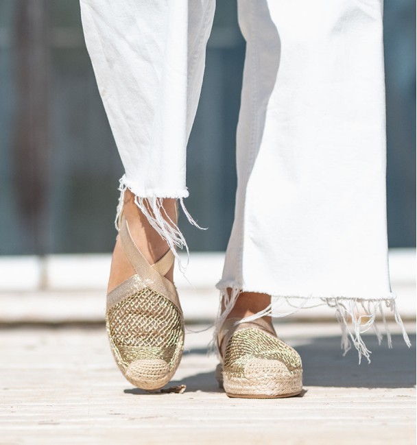 Alpargatas douradas com tiras elásticas cruzadas no peito do pé e biqueira original em tecido. Sem animais