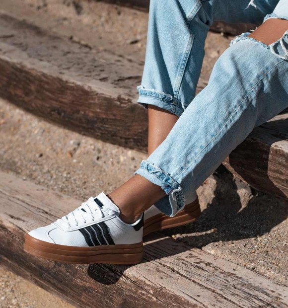 white trainers with double brown rubber sole and 4 black stripes. Animal free. 2
