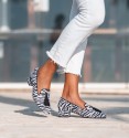 White and black wide low heel shoes, zebra print, trim and tassels in black. Textile material imitation natural hair.