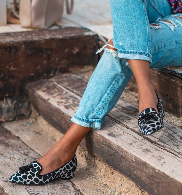 Sapatos de salto baixo com estampado de vaca preto e branco. Rebordo preto e borlas. Sem animais.