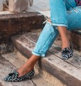 Sapatos de salto baixo com estampado de vaca preto e branco. Rebordo preto e borlas. Sem animais.