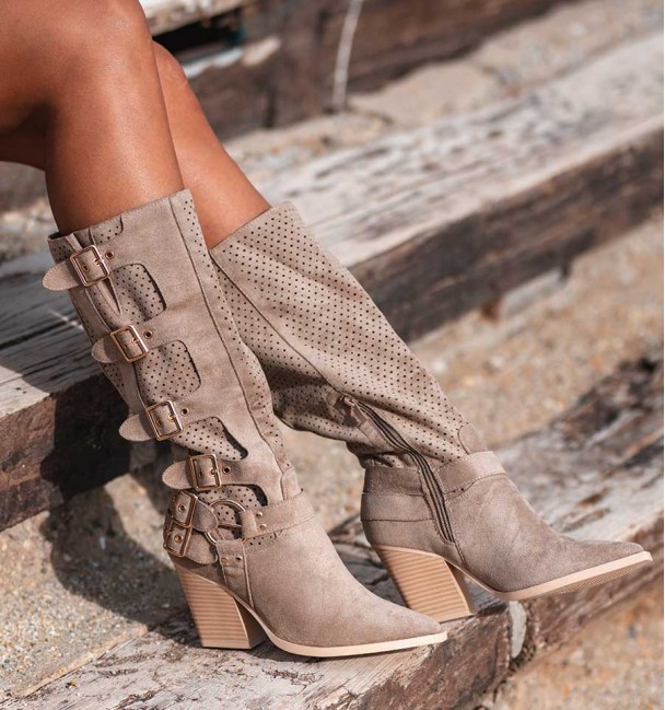 Botas altas estilo cowboy com fivelas laterais e cano perfurado. Cor tostada (caqui) e salto. Têxteis