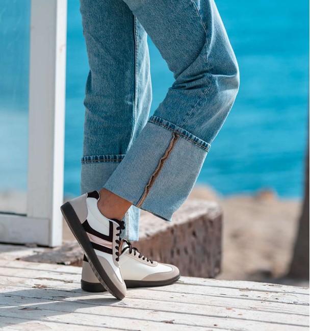 zapatillas deportivas combinadas en serraje gris, cuerina blanca y lineas marrones y doradas. Suela goma marrón