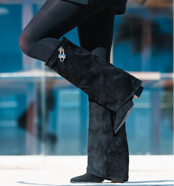 Black women's tall boots with flap and heel. Strap and padlock on the top