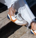 zapatillas deportivas blancas con puntera en serraje y detalle naranja y talón azul.