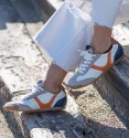white sneakers with suede toe cap and orange detail and blue heel.
