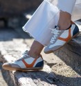 white sneakers with suede toe cap and orange detail and blue heel.