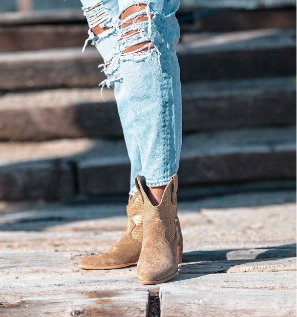 Botas bege estilo cowboy com cano entrelaçado e salto médio.