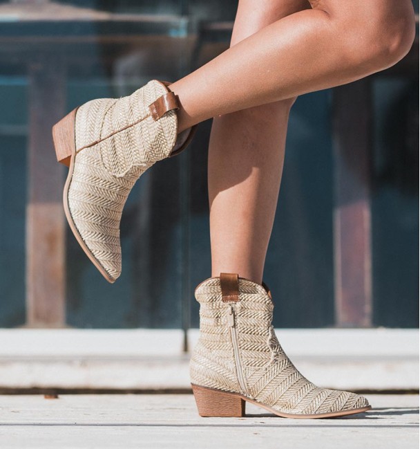 Beige cowboy boots with texture on the shaft and brown leather handles