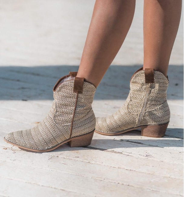 Beige cowboy boots with texture on the shaft and brown leather handles