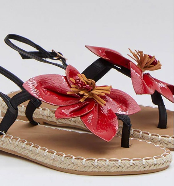 Sandalias planas con suela de cuerina y esparto tejido con original flor roja en el empeine.